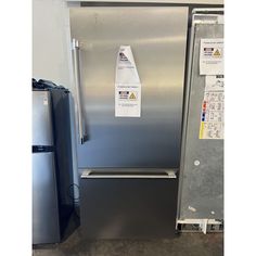 a stainless steel refrigerator and freezer combo in a room with tags on the door