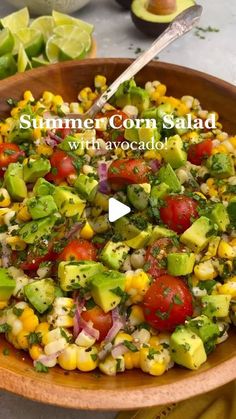 a wooden bowl filled with corn and avocado salad on top of a table