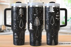 three travel mugs with christmas trees and snowflakes on them sitting on a table