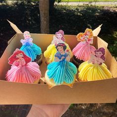 there are cupcakes that have been decorated like princesses in the box and on top of each other