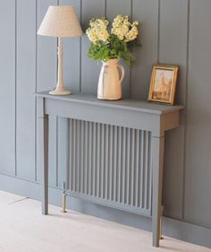 a vase with flowers sitting on top of a table next to a lamp and framed photograph