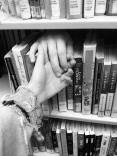 two people holding hands in front of a book shelf filled with books and other books