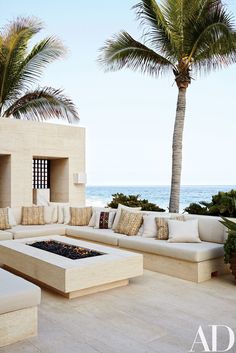 an outdoor seating area with palm trees and the ocean in the background