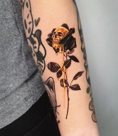 a woman's arm with a rose tattoo on it and a skull in the middle