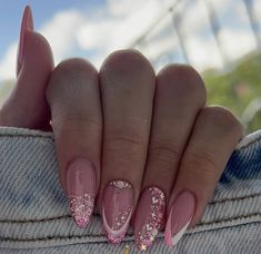 a woman's hand with pink and white nail polish on it, holding onto her jeans