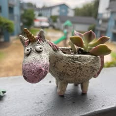 a small toy horse with a plant in it's mouth sitting on a ledge