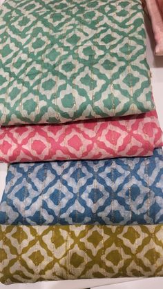 four different colors of fabric stacked on top of each other in a row and one is pink, green, blue