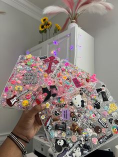 a person holding up a clear case with lots of stickers on it