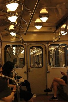 people are sitting on the subway train and looking at their cell phones as they read