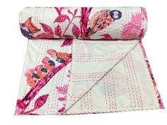 a pink and white floral print blanket folded on top of each other