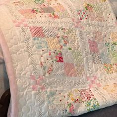 a close up of a quilt on a bed with a pillow in the foreground