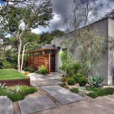 a modern house with landscaping and trees in the front yard