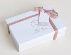 a white box with a pink ribbon and a tag on the top that says lizush