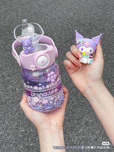 a hand holding a purple and white bottle with an animal figurine in it