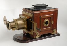 an old fashioned camera sitting on top of a wooden stand