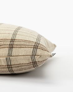 a close up of a pillow on a white surface with a black and brown checkered pattern