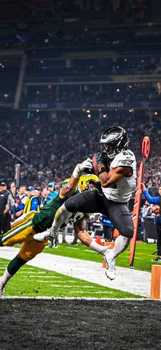 a football player jumping into the air to catch a ball while being tackled by another player