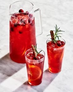 two glasses filled with red liquid and garnished with rosemary