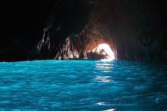 there is a boat in the water and it is going into a cave with light coming out