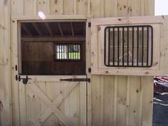 an open barn door with bars on the top and bottom panels, in front of a wooden wall