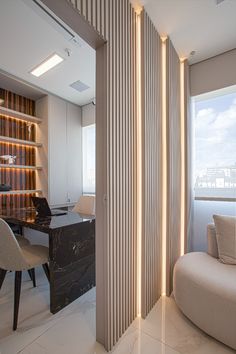 a room with a couch, desk and bookshelf next to a large window