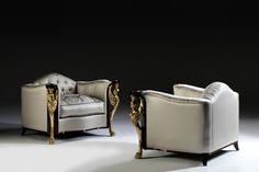 two white chairs sitting next to each other in front of a black background with gold accents