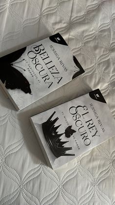 two books sitting on top of a bed next to each other in front of a white blanket