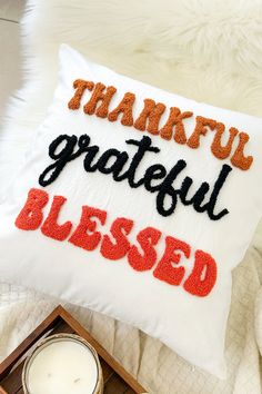 a white pillow that says grateful, grateful, and blessed on it next to a candle