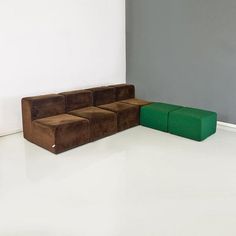 a green and brown couch sitting on top of a white floor next to a gray wall