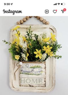 a white frame with yellow flowers in it and a sign that says home hanging on the wall