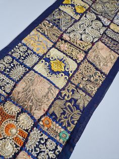 a blue and gold patchwork table runner on a white surface with an orange flower in the center