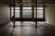 an empty room with wooden floors and windows