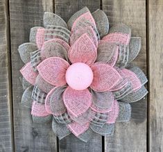 a pink and gray mesh flower on a wooden fence