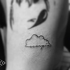 black and white photo of a woman's stomach with a small cloud tattoo on it