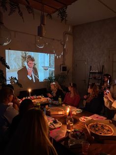 a group of people sitting around a table with pizza and drinks in front of them