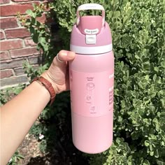 a hand holding a pink insulated water bottle