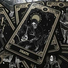 some black and gold playing cards with skeleton images on the front one has a skull holding a guitar