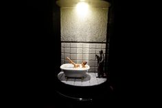 a bathtub in the dark with two wooden spoons sticking out of it's side