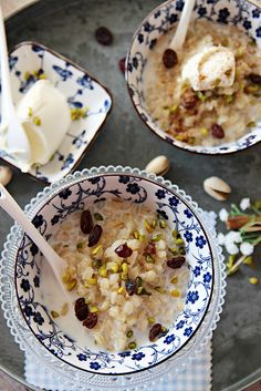 two bowls filled with oatmeal and nuts on top of a table next to spoons