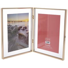 an open photo frame with a sunset over the water and rocks on the shore in front of it