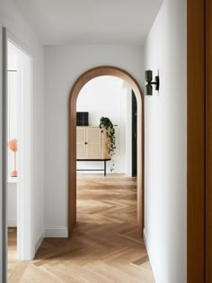 an arch in the hallway leads to a living room with a plant on the far wall