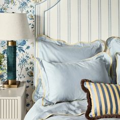 a bed with blue and yellow pillows on top of it next to a night stand