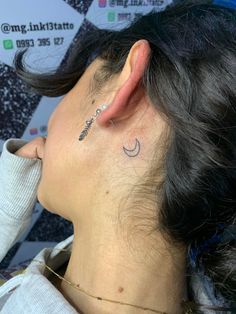 a woman with a small crescent tattoo on her left side behind her ear, looking to the right