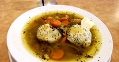 a white bowl filled with soup on top of a wooden table