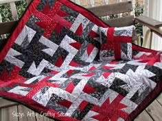 a red and black quilt sitting on top of a wooden bench