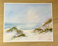 a watercolor painting of a beach scene with sand dunes and sea oats in the foreground