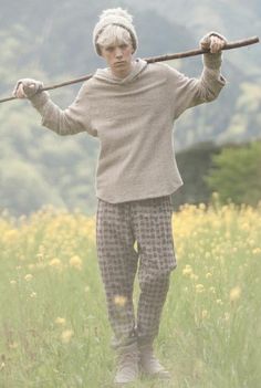 an old woman is standing in the grass with a stick on her shoulder and wearing pajamas