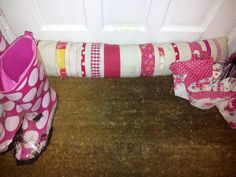 a pair of pink boots sitting on the floor next to a pile of blankets and pillows