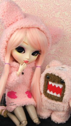 a doll is sitting next to a stuffed animal and wearing a pink outfit with teeth on it