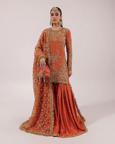 a woman in an orange and gold outfit with her hand on her hip, standing against a white background